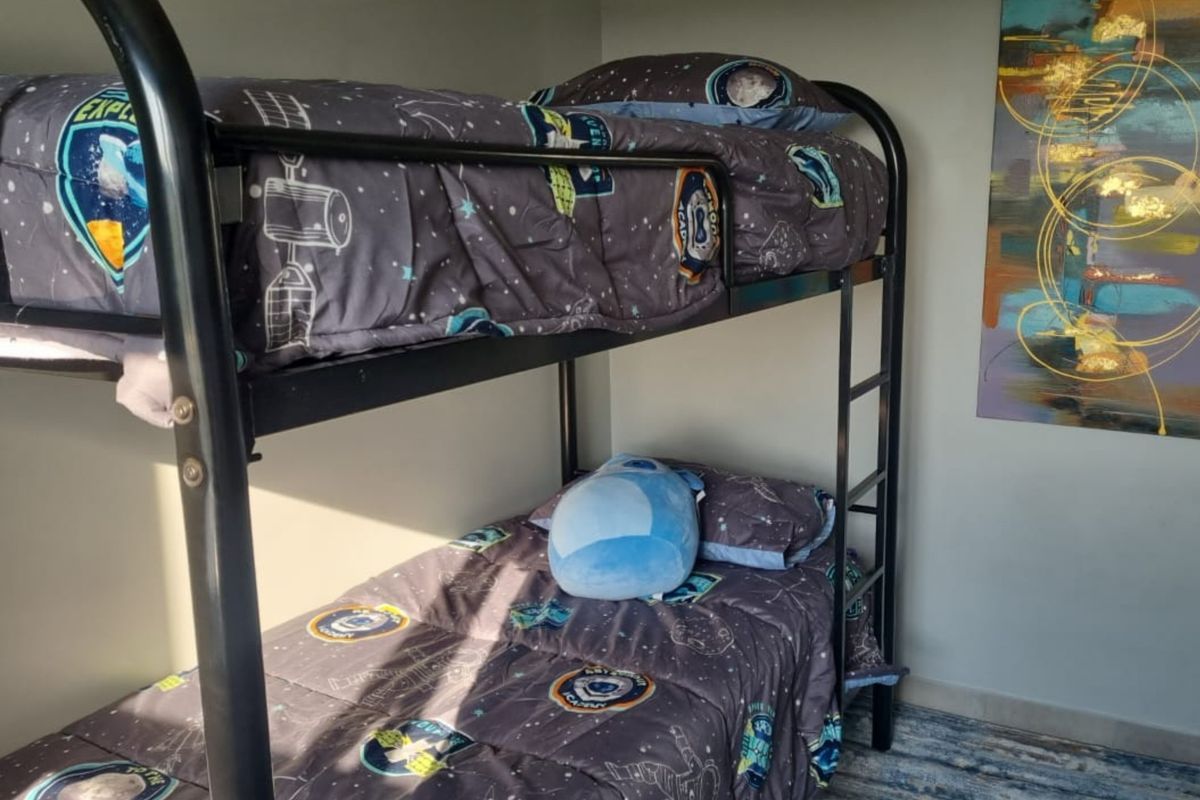 A bedroom featuring a metal bunk bed frame, neutral wall finishes, and tiled flooring.