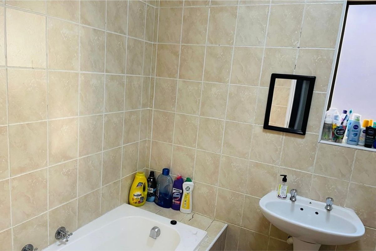 A functional bathroom featuring ceramic wall tiling, a pedestal washbasin, and a built-in bathtub with chrome fixtures.