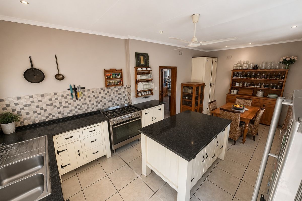 A well-maintained kitchen featuring a central island, granite countertops, tiled backsplash, and a built-in gas stove, seamlessly flowing into a dining area.