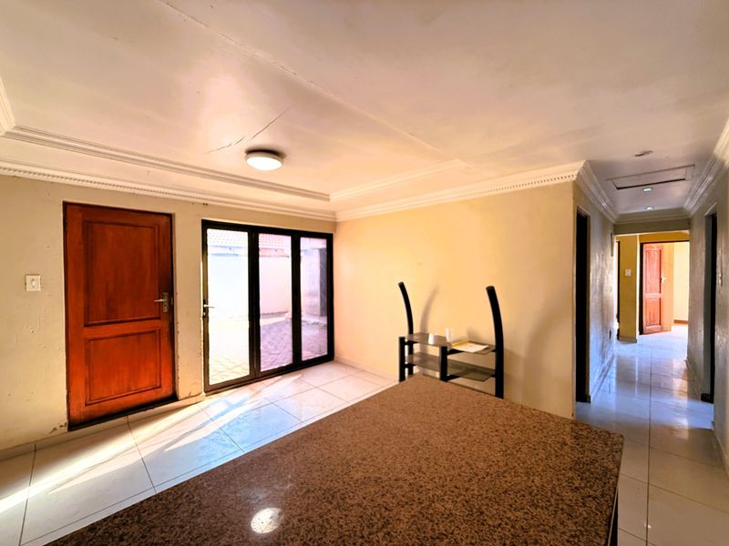 Open plan living area featuring tiled flooring, a granite countertop, and direct access to the exterior through a sliding glass door.
