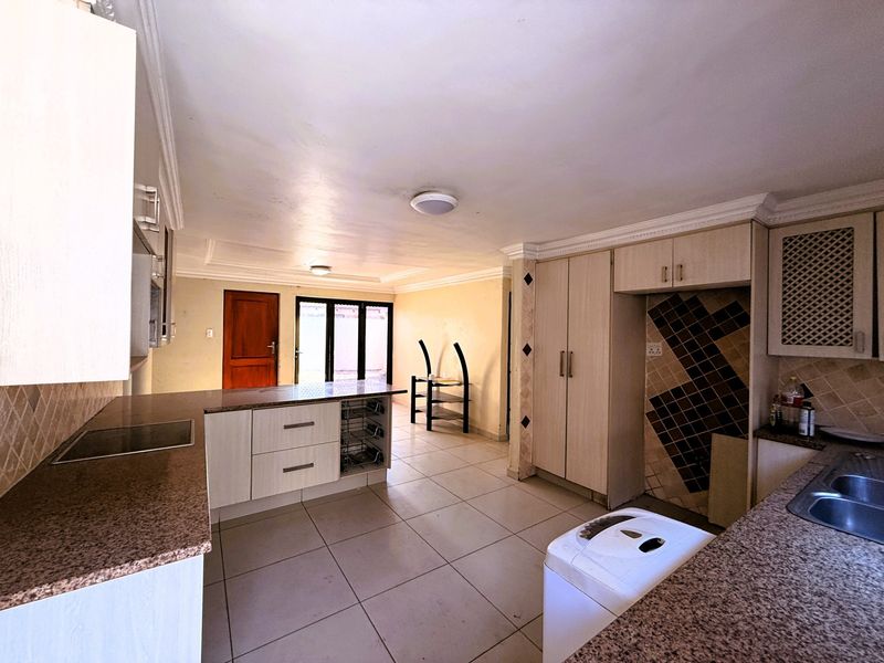 A functional kitchen featuring granite countertops, built-in cabinetry, and tiled flooring, offering a practical layout with potential for cosmetic updates.