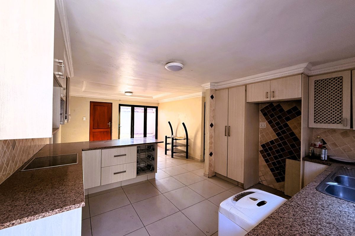 A functional kitchen featuring granite countertops, built-in cabinetry, and tiled flooring, offering a practical layout with potential for cosmetic updates.