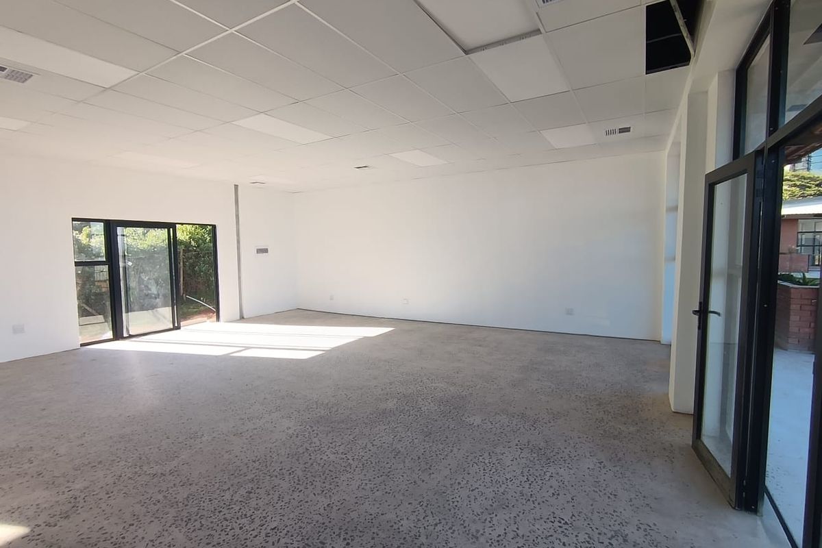 Spacious open-plan commercial area featuring polished aggregate concrete floors, suspended ceiling tiles, and large glass doors providing ample natural light.