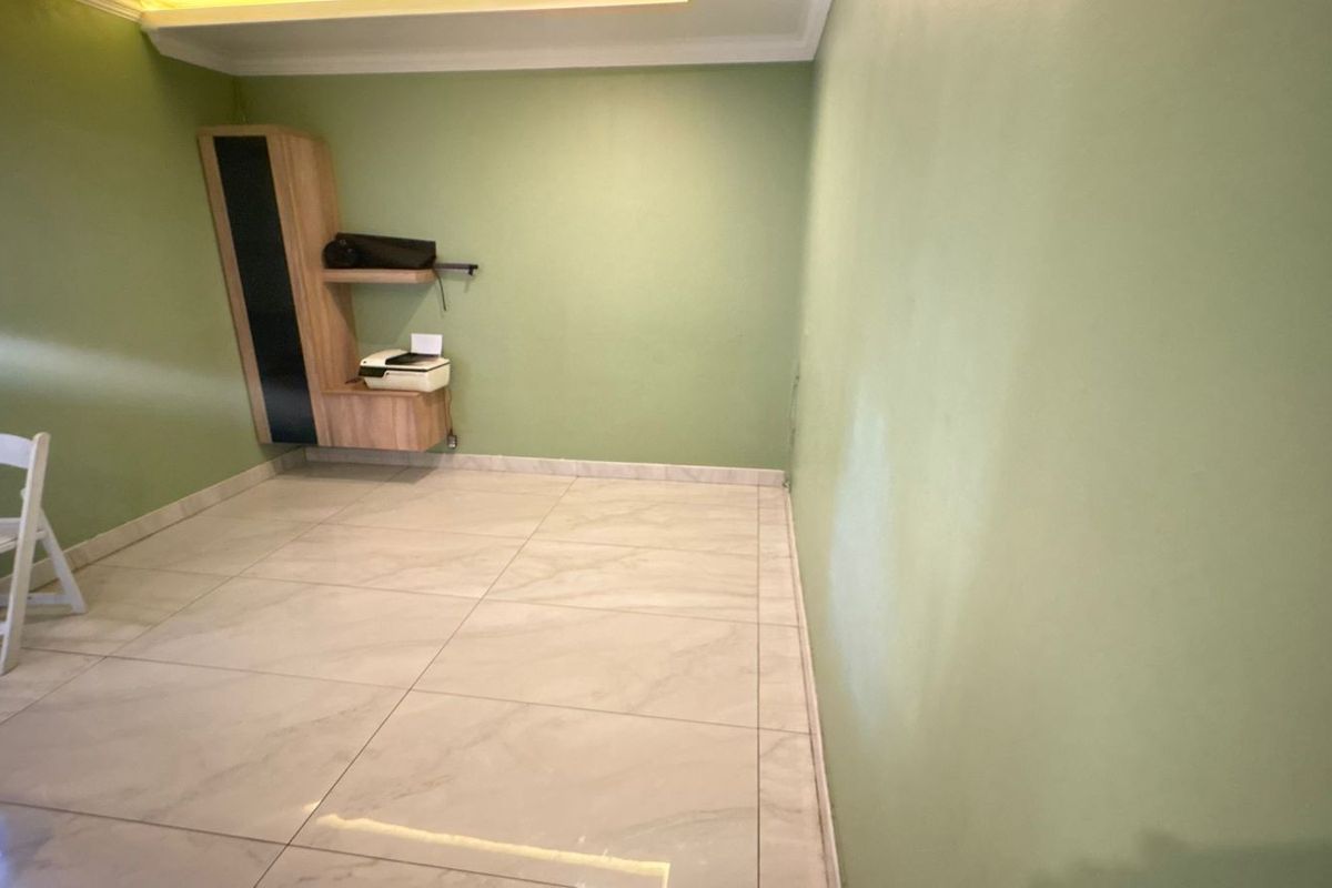 A simple room featuring light-colored floor tiles and green painted walls, including a small built-in wall-mounted storage unit.