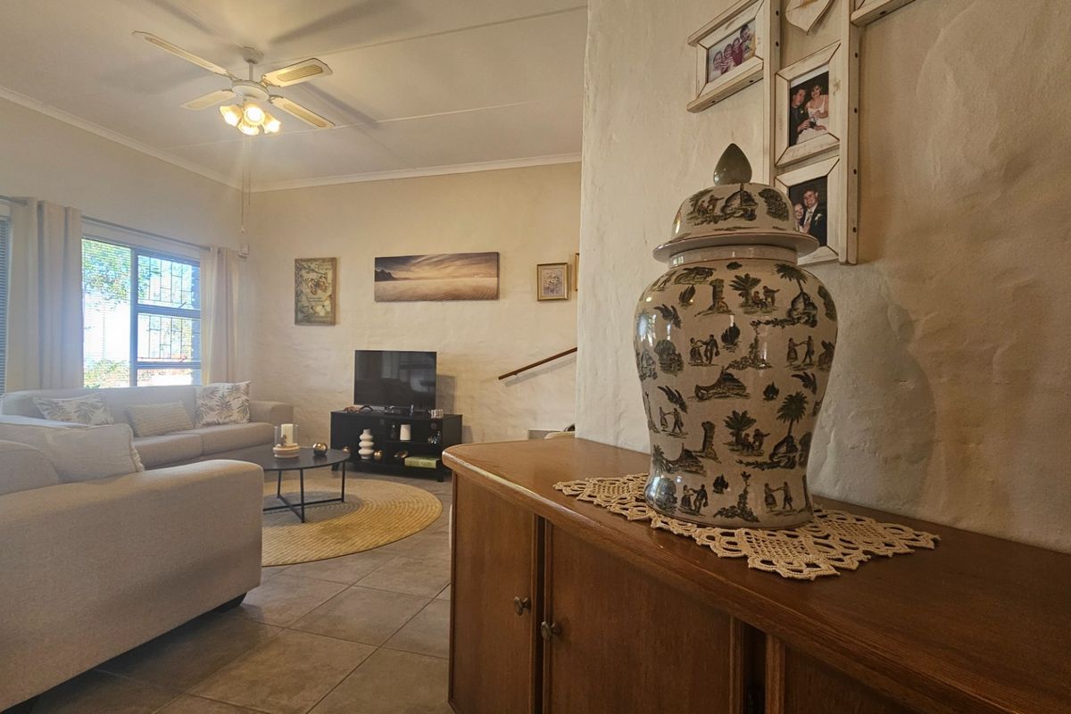 A comfortable living room featuring tiled flooring, a ceiling fan, and textured wall finishes, providing a bright and inviting space for relaxation.