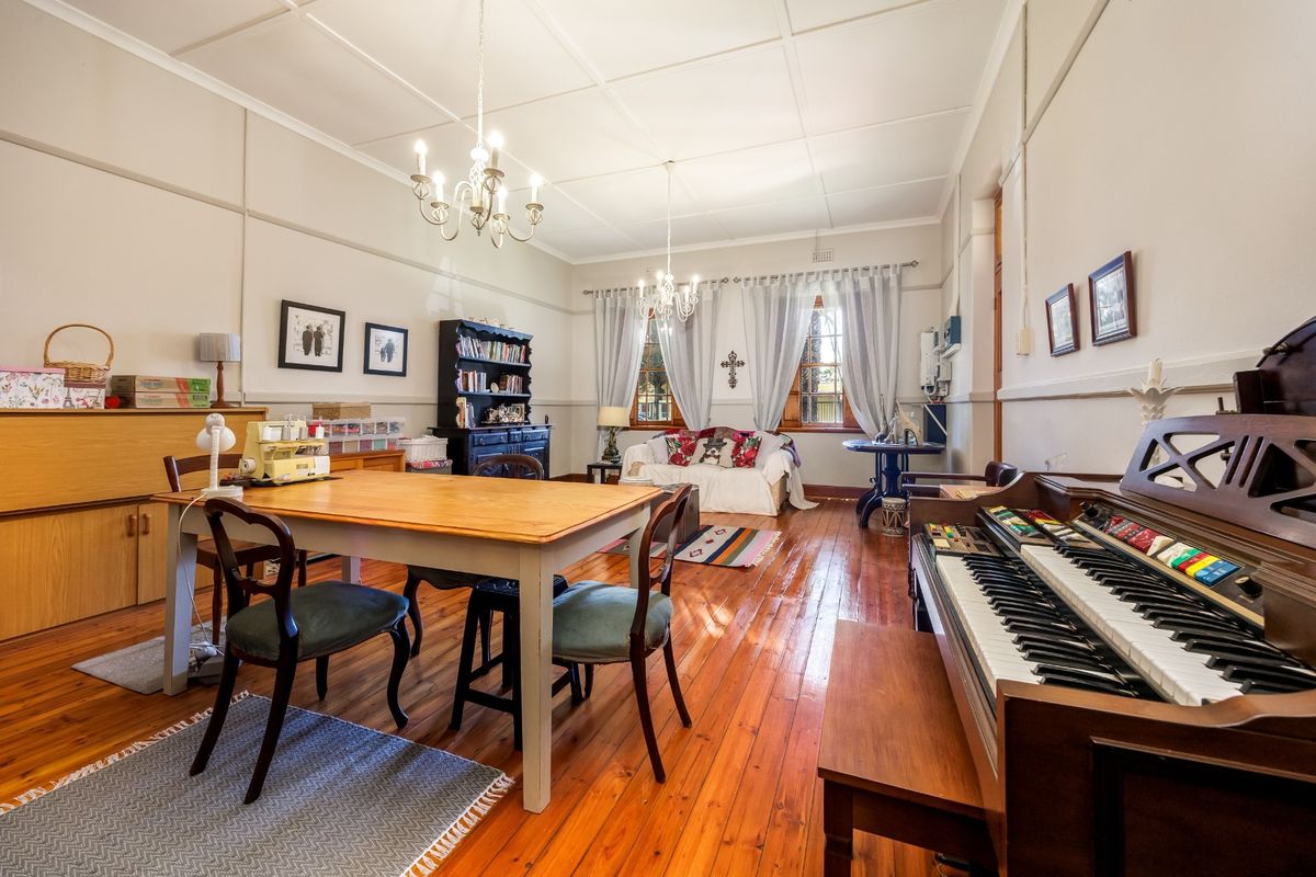 Spacious living area featuring original polished timber flooring, high ceilings with decorative molding, and classic chandelier lighting, offering a warm and traditional atmosphere.