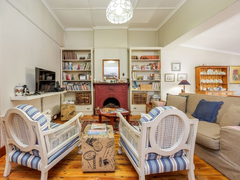 A cozy living room featuring a prominent brick fireplace, built-in shelving units, and original timber flooring, creating a warm and inviting atmosphere.