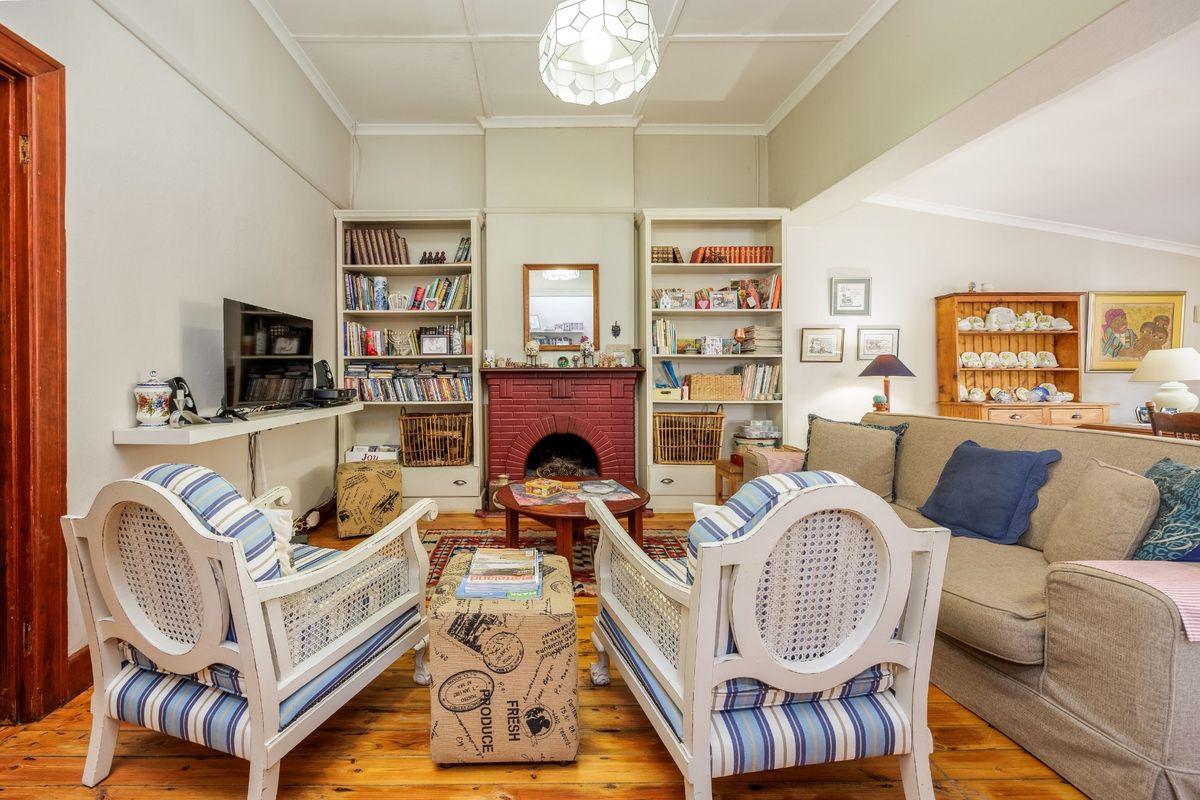 A cozy living room featuring a prominent brick fireplace, built-in shelving units, and original timber flooring, creating a warm and inviting atmosphere.