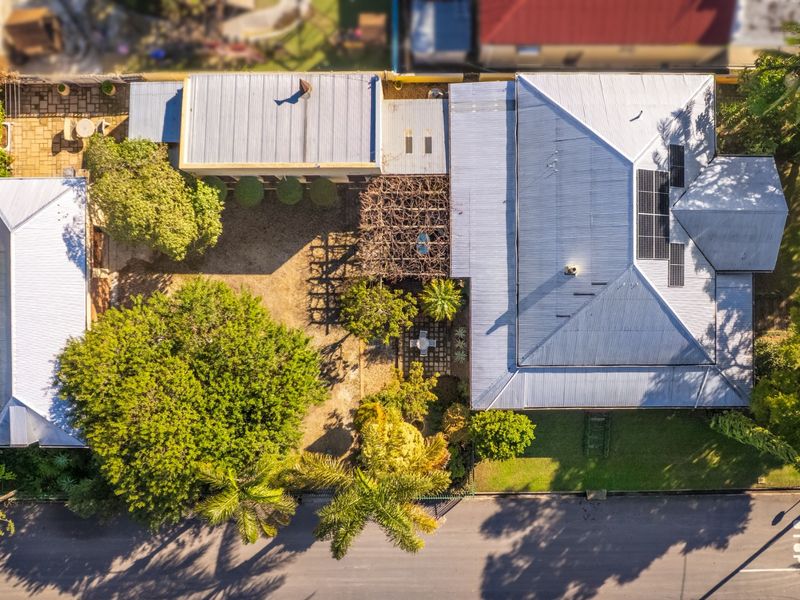 Aerial view of the property showing the main house, detached structure, garden area, and roof-mounted solar panels.