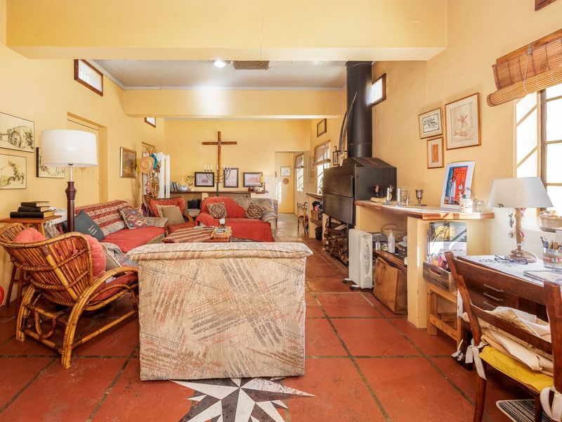 Spacious living area featuring terracotta tiled flooring, a built-in fireplace, and large windows allowing for natural light.