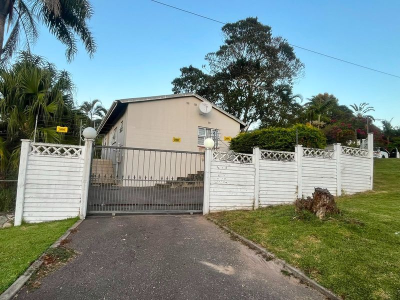 Front exterior view of the property featuring a gated driveway, perimeter fencing, and a single-story house structure with a satellite dish.