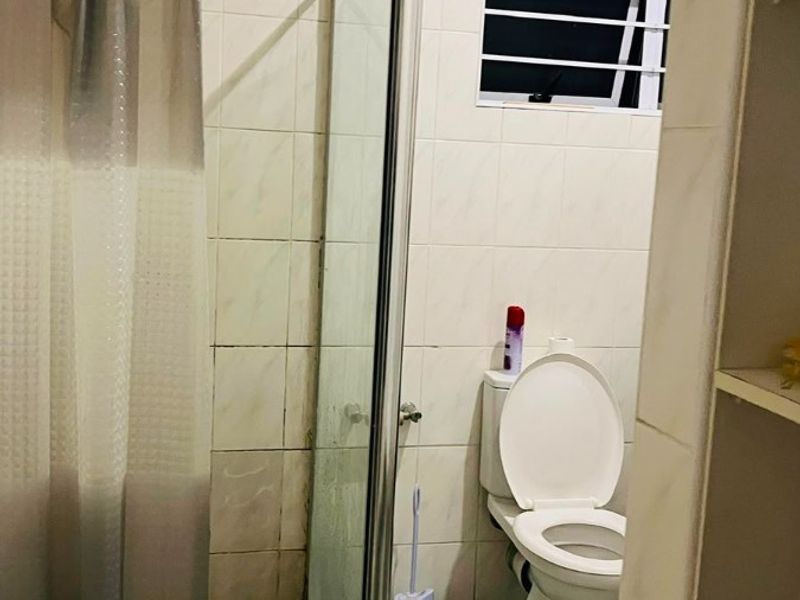 A functional bathroom featuring a glass-enclosed shower, tiled flooring, and a standard toilet.