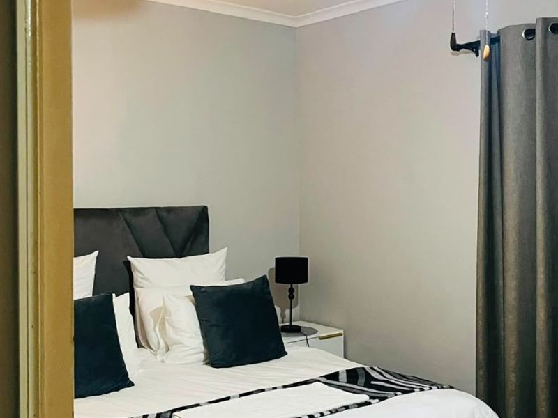 A bedroom featuring a ceiling fan and tiled flooring, viewed through a doorway.