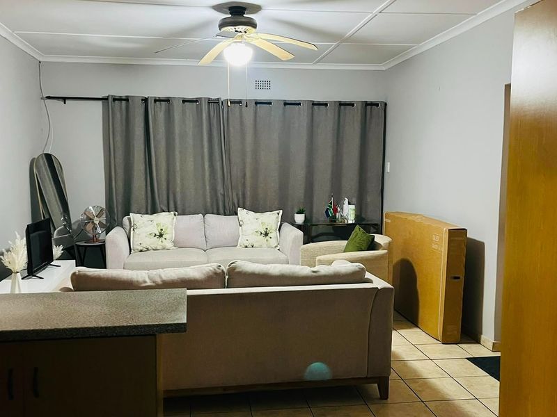 A living room area featuring tiled flooring, a ceiling fan, and neutral wall finishes, providing a functional space for relaxation.