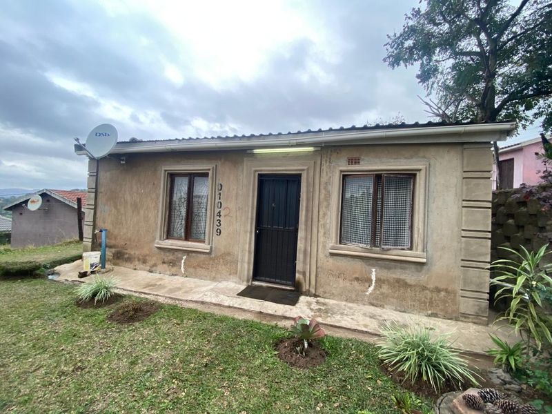 Front elevation of a single-story house featuring a concrete path, security gate, and satellite dish installation.