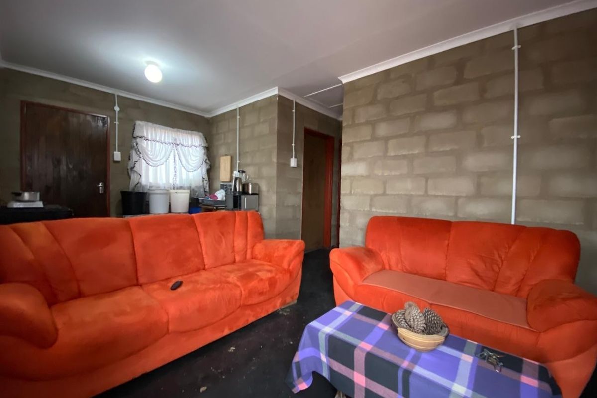 A living area featuring exposed concrete block walls, surface-mounted electrical conduit, and basic interior finishes.