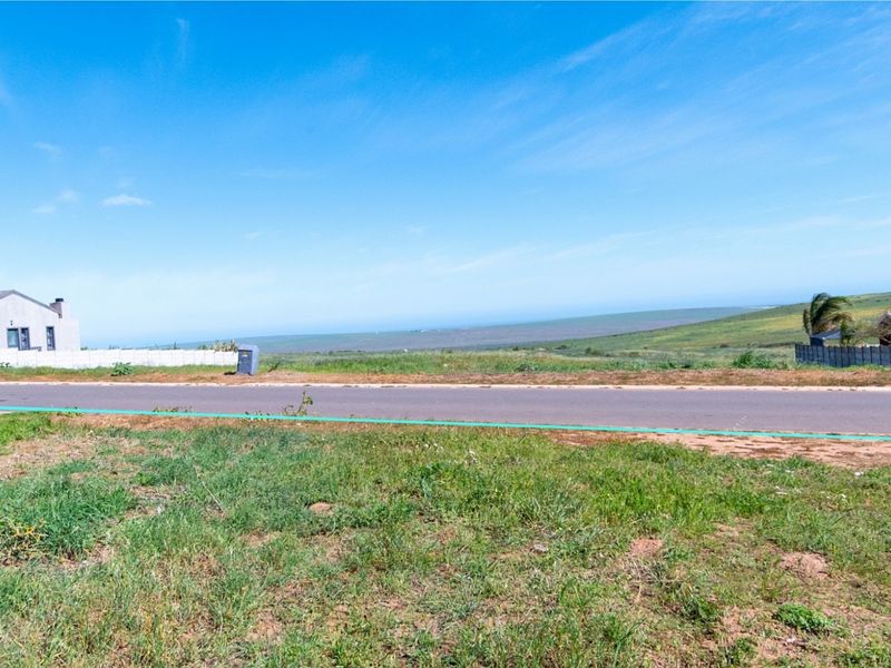 A view of the vacant residential land overlooking a paved road and expansive natural landscape.