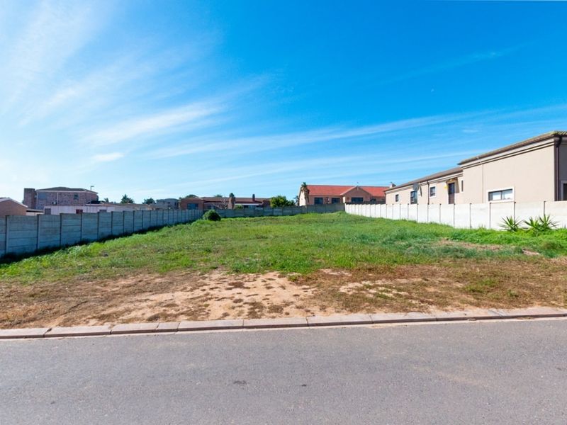 A vacant residential plot featuring a level grass surface and precast concrete boundary walls, situated in a developed neighborhood.