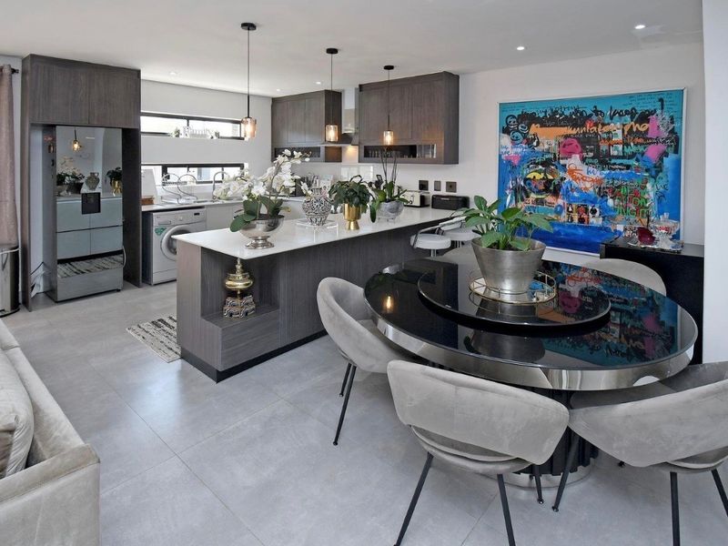 Modern open-plan living and kitchen area featuring sleek dark cabinetry, a central island with stone countertops, and contemporary tiled flooring throughout.