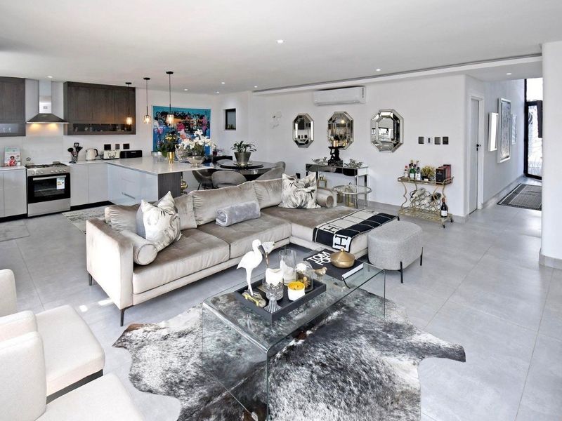 Modern open-plan living area featuring a sleek kitchen with island, tiled flooring, and integrated air conditioning, creating a bright and cohesive living space.