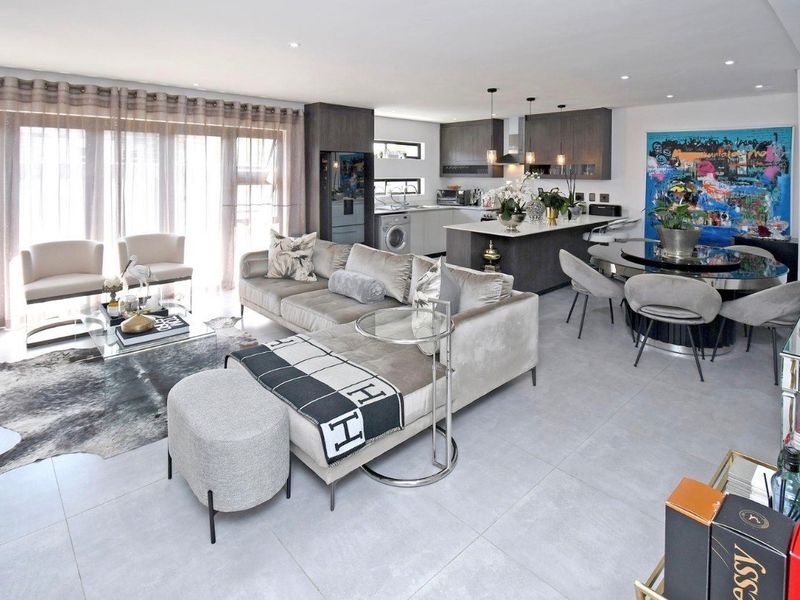 Modern open-plan living area featuring a sleek kitchen with island, tiled floors, and large sliding doors providing ample natural light.