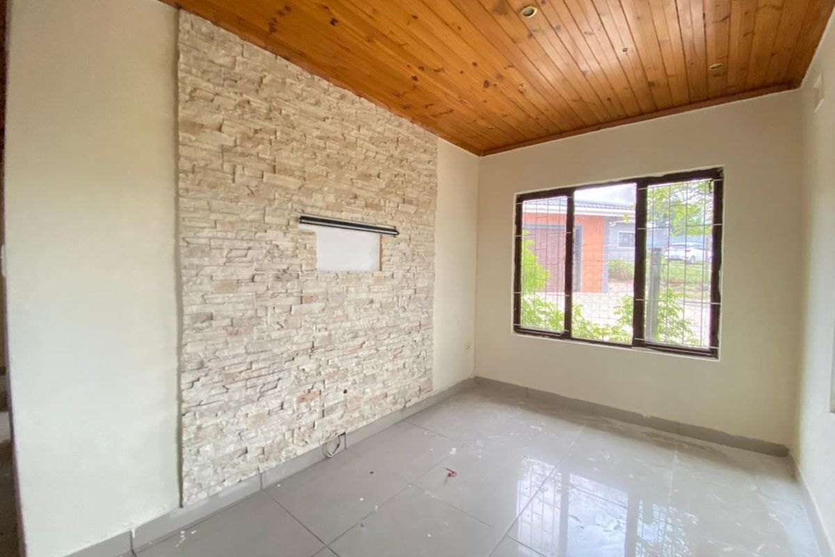 A bright living room featuring a textured stone feature wall, polished tile flooring, and a warm timber-paneled ceiling with recessed lighting.