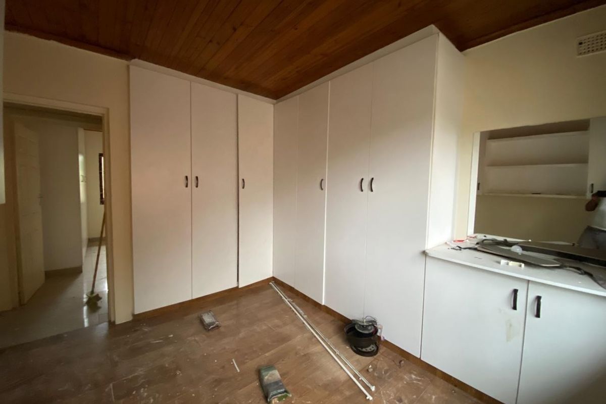 A bedroom featuring built-in white cabinetry, a wooden ceiling, and tiled flooring, offering ample storage space.