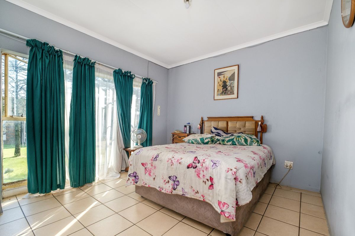 A bedroom featuring tiled flooring and large sliding glass doors providing direct access to the garden area.