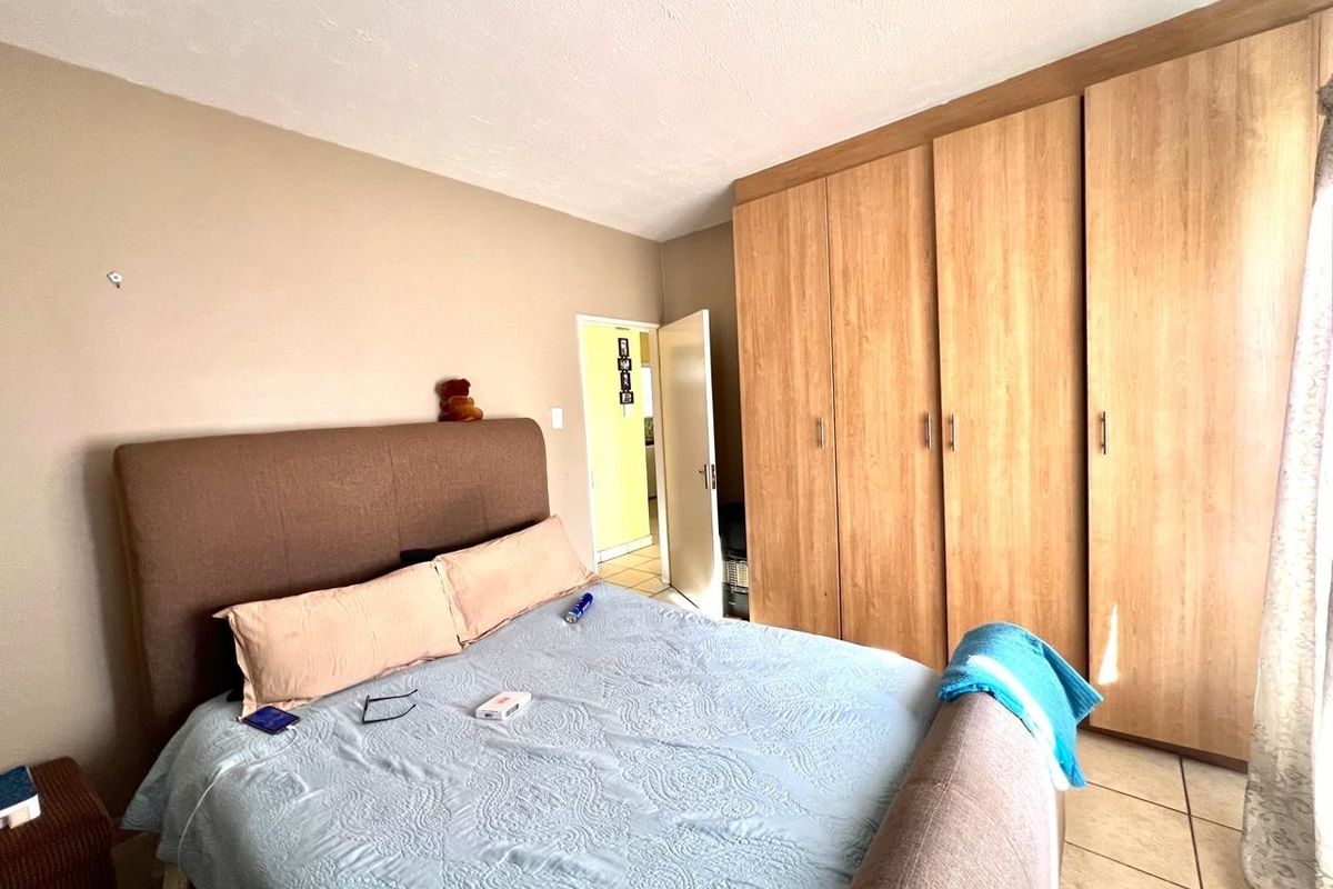A bedroom featuring built-in wooden wardrobes and tiled flooring, providing functional storage space within the apartment.