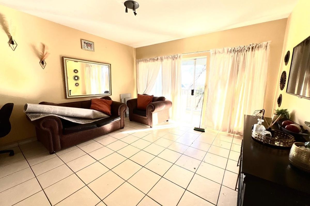 A living room featuring tiled flooring and sliding glass doors that provide access to an outdoor balcony area.