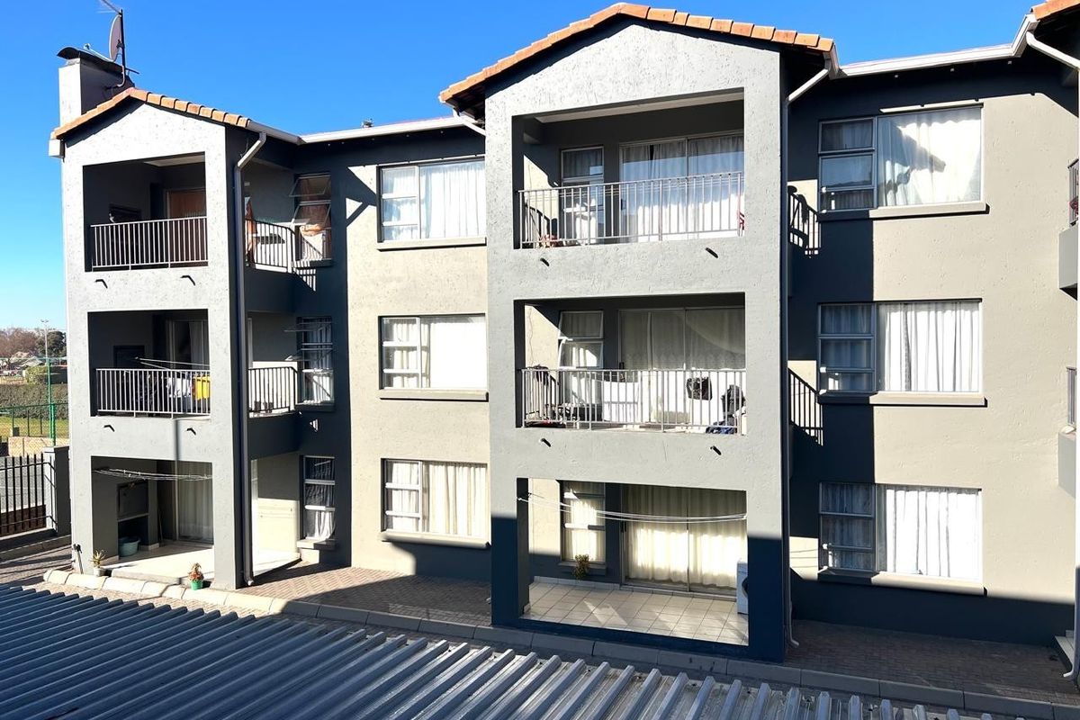 Exterior view of a multi-story apartment complex featuring private balconies, tiled flooring, and metal railings on each level.