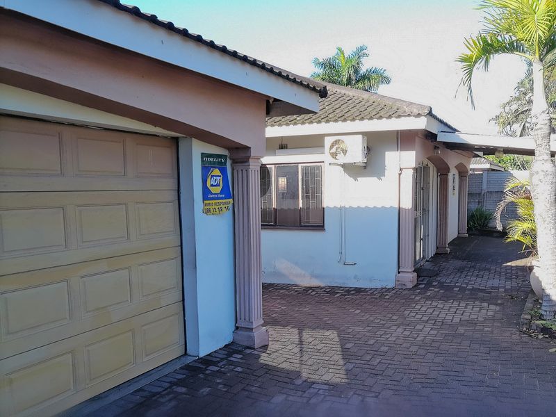 Front exterior view of the property featuring a garage, paved driveway, and decorative columns with an installed air conditioning unit.