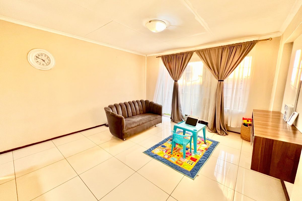 A bright living room featuring large format floor tiles and a sliding glass door that provides access to the exterior.