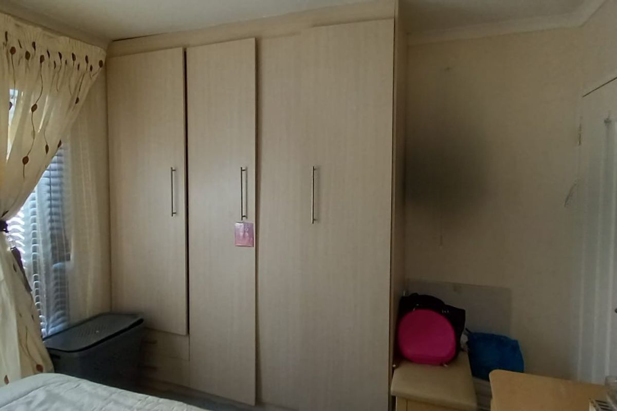 A bedroom featuring built-in wooden cabinetry and a window with fitted blinds.