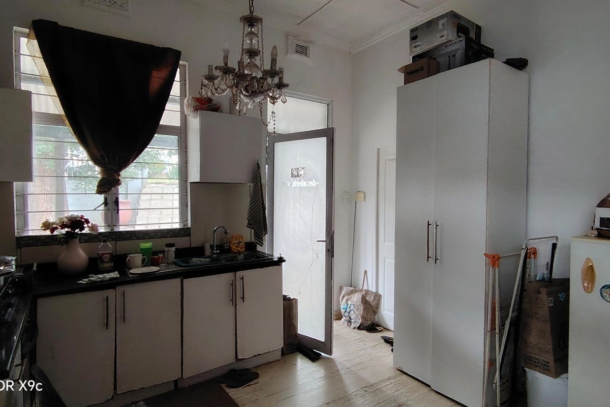 A compact kitchen area featuring built-in cabinetry, a sink, and a glass-panelled door leading to the exterior.