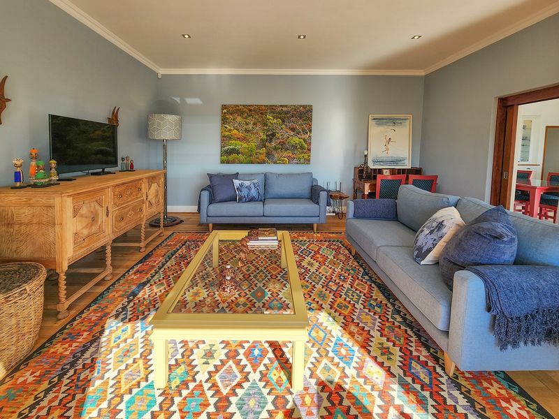A well-lit living room featuring hardwood flooring, recessed ceiling lighting, and crown molding, providing a comfortable and inviting space for relaxation.