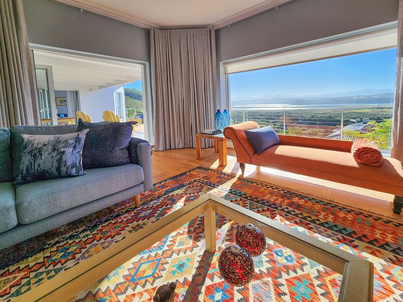 Spacious living room featuring large windows with panoramic landscape views, hardwood flooring, and seamless access to an outdoor patio area.