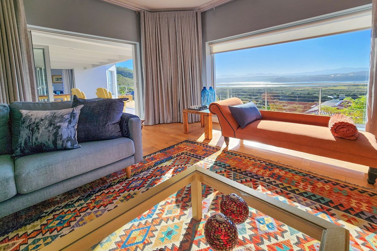 Spacious living room featuring large windows with panoramic landscape views, hardwood flooring, and seamless access to an outdoor patio area.