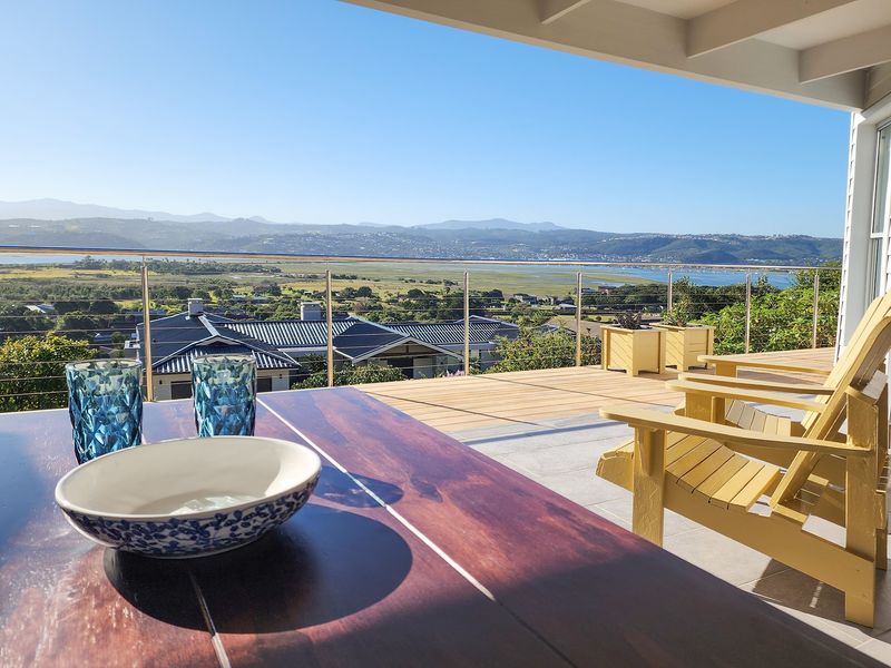 Covered patio featuring timber decking, stainless steel cable railing, and expansive panoramic views of the surrounding landscape and estuary.