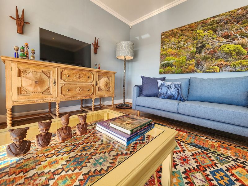 A comfortable living room featuring crown molding, hardwood flooring, and a neutral wall finish, creating a warm and inviting atmosphere.