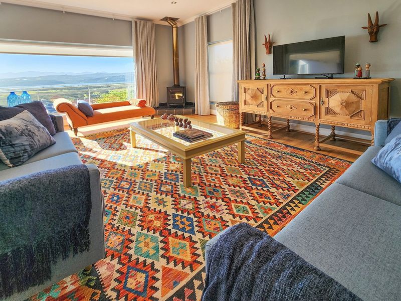 Spacious living room featuring a freestanding wood-burning fireplace, large windows with panoramic landscape views, and polished timber flooring.