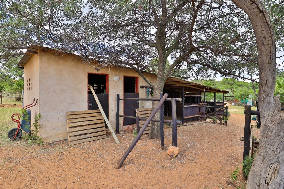 Rustic farm outbuilding featuring stable-style stalls with timber framing and a covered lean-to area, situated in a natural outdoor setting.