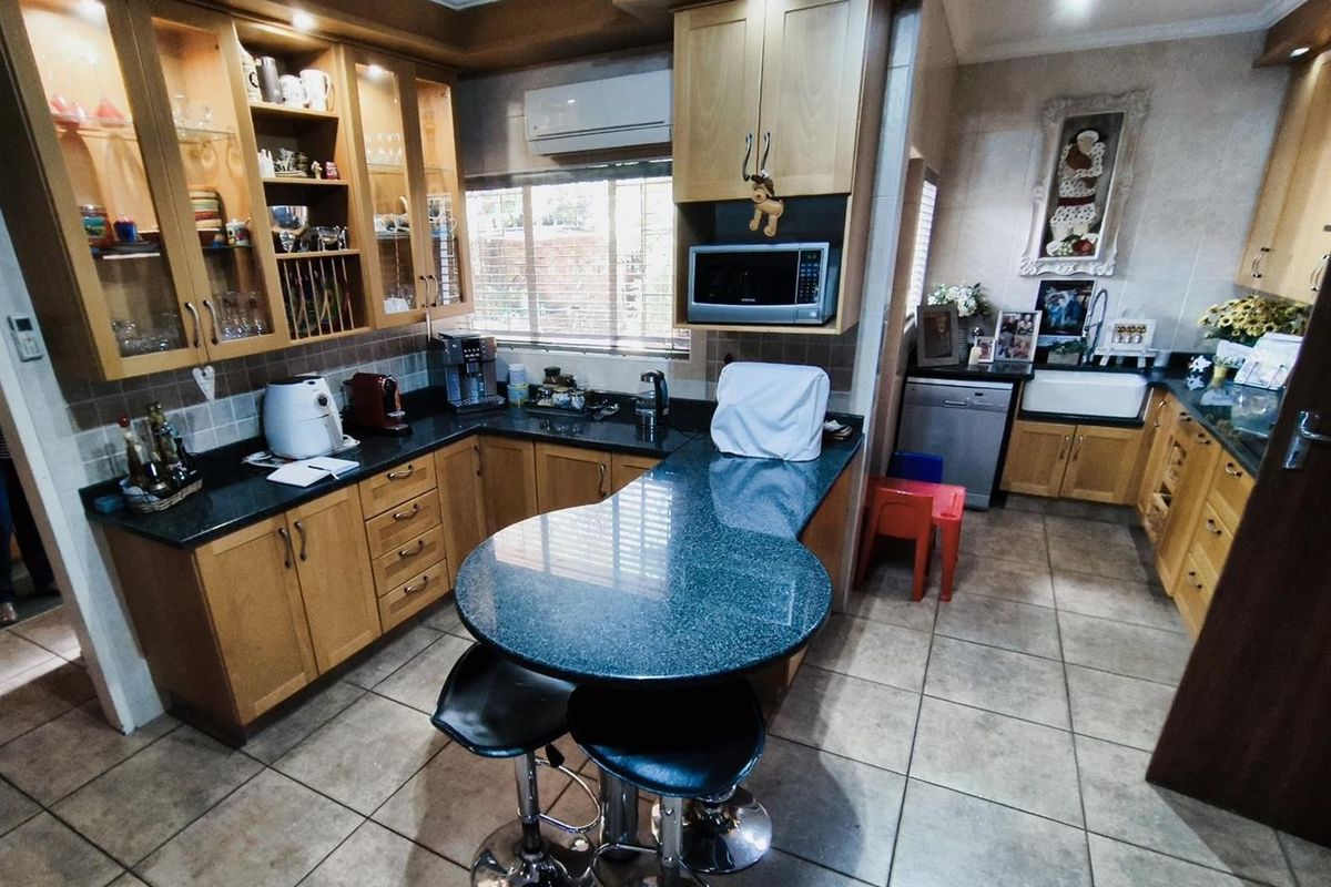 A functional kitchen featuring light wood cabinetry, dark granite countertops, a breakfast bar, and tiled flooring with integrated appliance spaces.