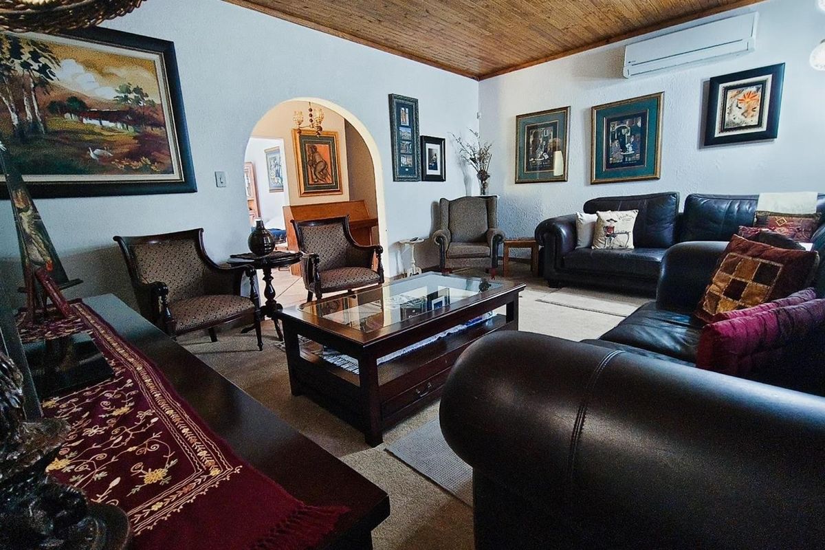 A spacious living room featuring a timber-clad ceiling, arched doorway, and wall-mounted air conditioning unit.