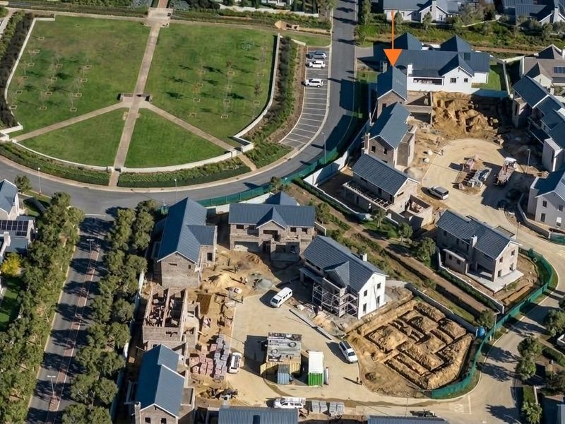 Aerial view of a residential estate development showing multiple houses in various stages of construction and surrounding infrastructure.