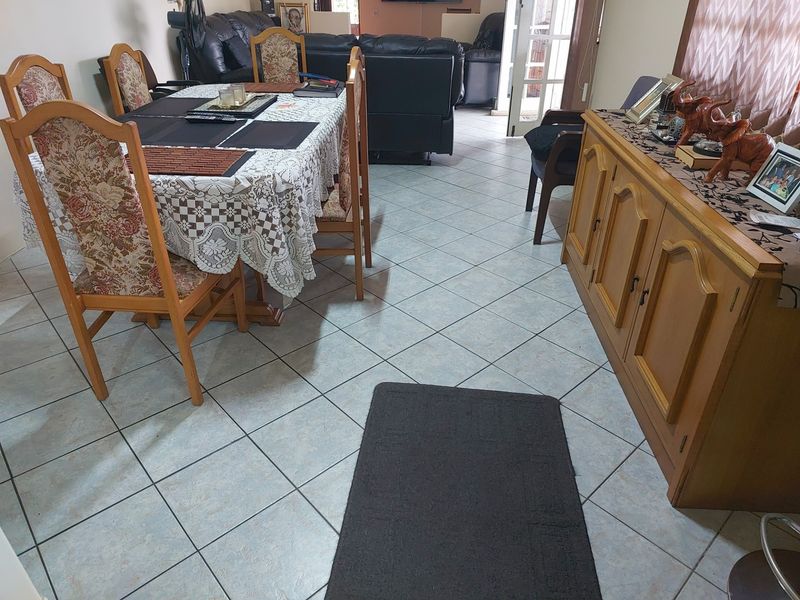 Open plan living and dining area featuring light-toned ceramic floor tiles throughout.