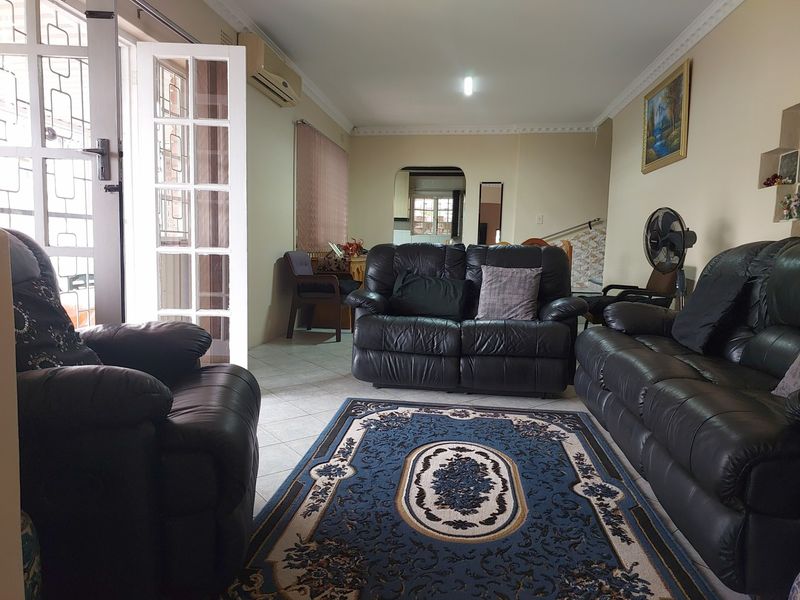 A living room featuring tiled flooring, crown molding, and a wall-mounted air conditioning unit, with access to an outdoor area through French doors.