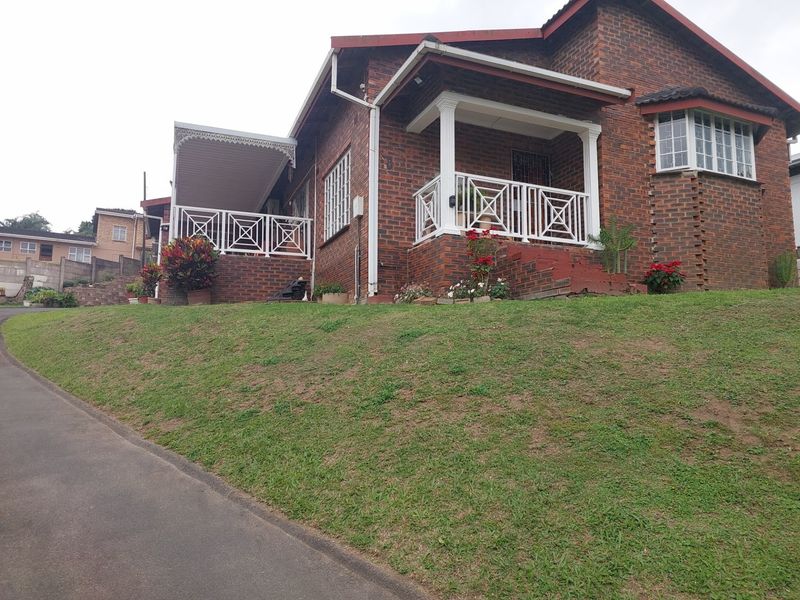 A charming face-brick house featuring a covered front porch with decorative white railings and a well-maintained exterior facade.