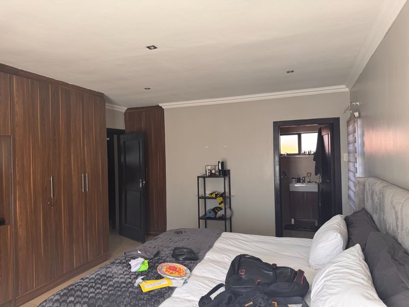 A well-maintained bedroom featuring extensive built-in wooden cabinetry, recessed ceiling lighting, and direct access to an en-suite bathroom.
