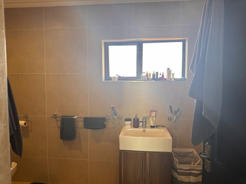 A functional bathroom featuring tiled walls, a modern vanity cabinet with a ceramic basin, and chrome fixtures.
